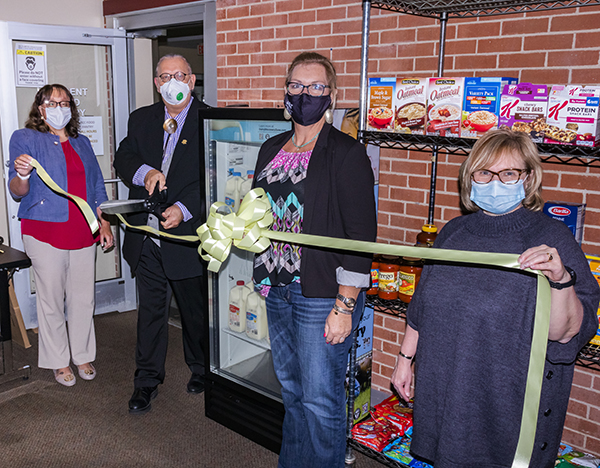 President Bryant cuts the ribbon unveiling the new cooler donated to the student food pantry.