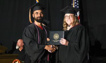 Redlands graduate is handed diploma by Interim President Jena Marr