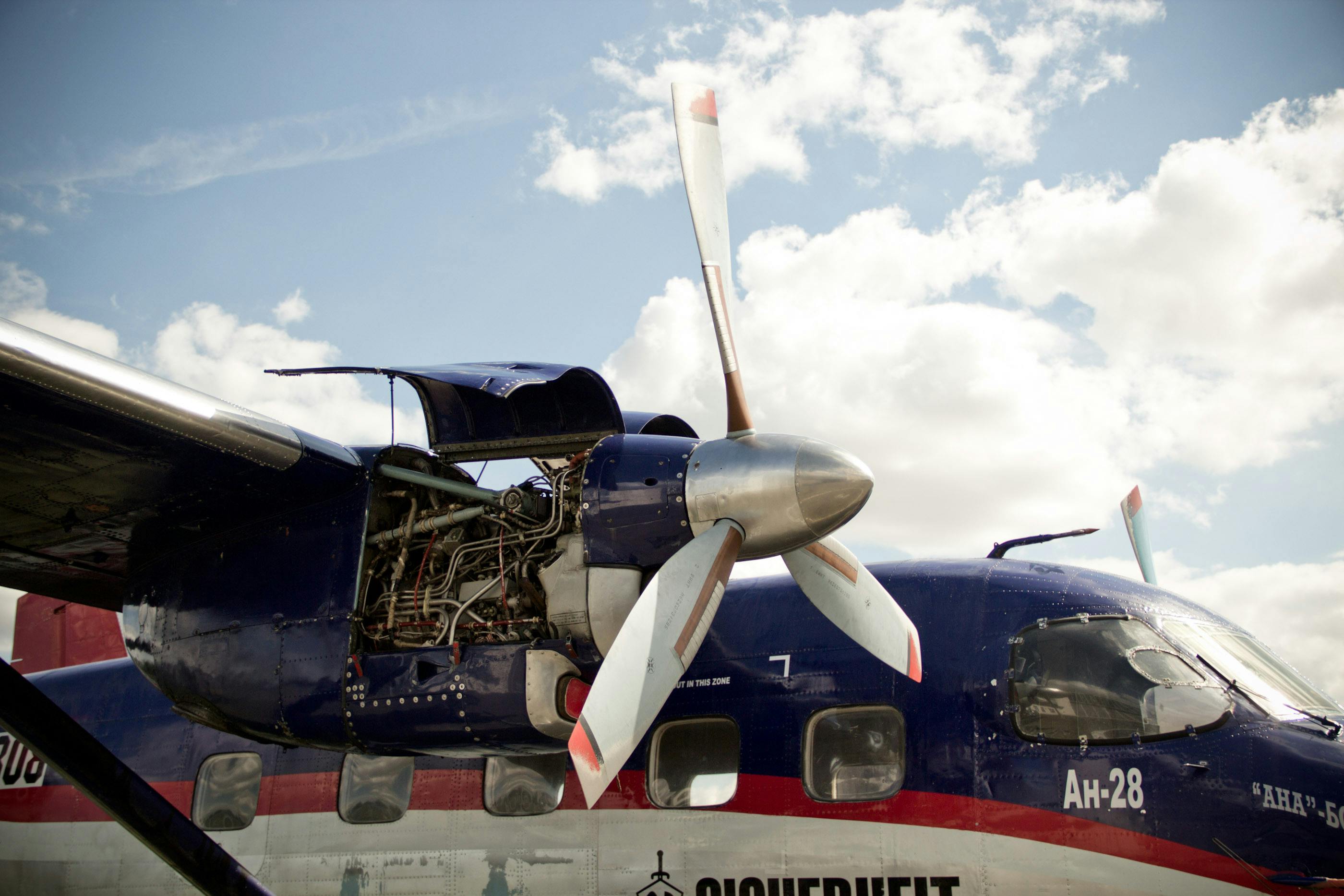 A twin-engine prop plane with engine bay covers open for maintenance