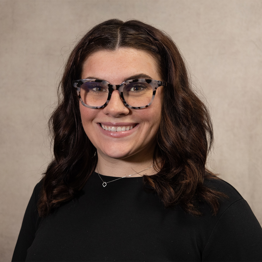 Smiling woman in a black sweater and speckled glasses
