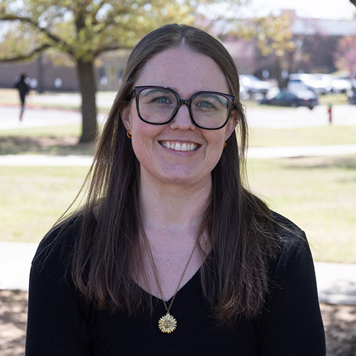 Woman with long dark hair and glasses