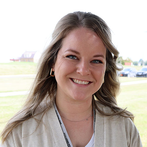 Smiling woman with light brown hair wearing a white sweater