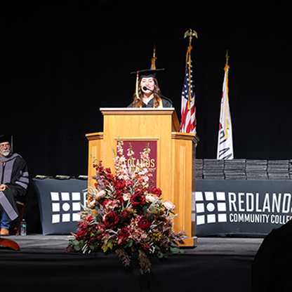 Graduate makes speech at lectern on stage