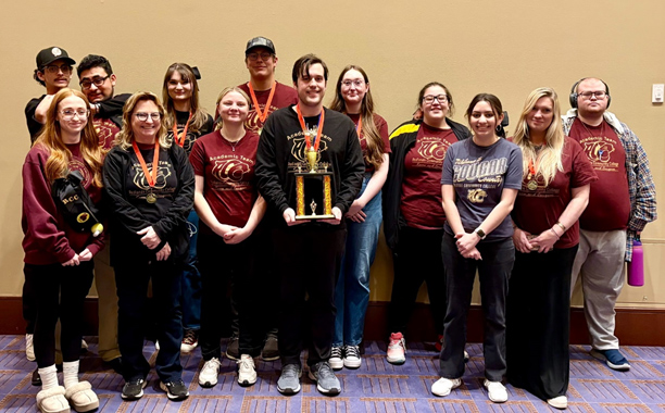 Thirteen students stand in a line, displaying their trophy and medals