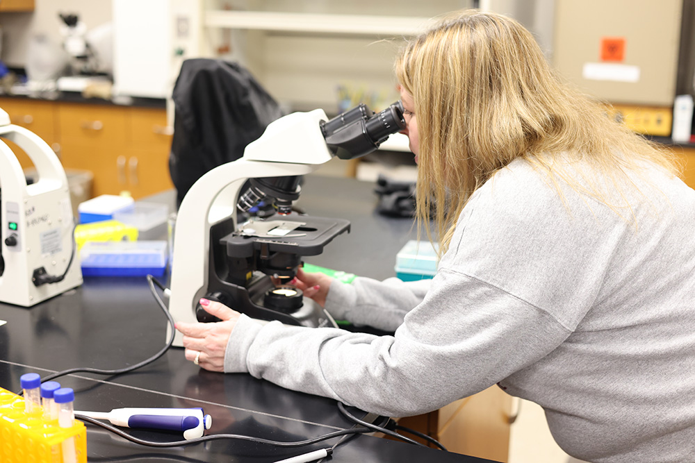 Woman looks into a microscope