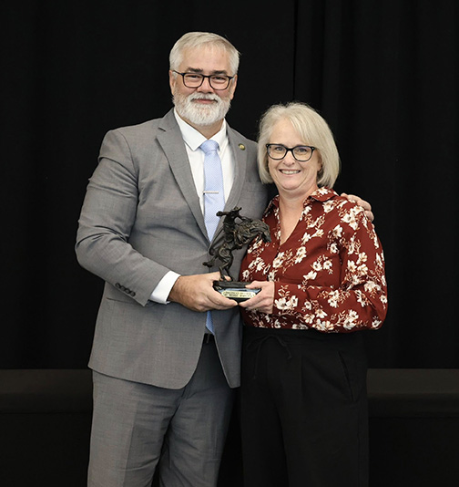 Man hands award to woman