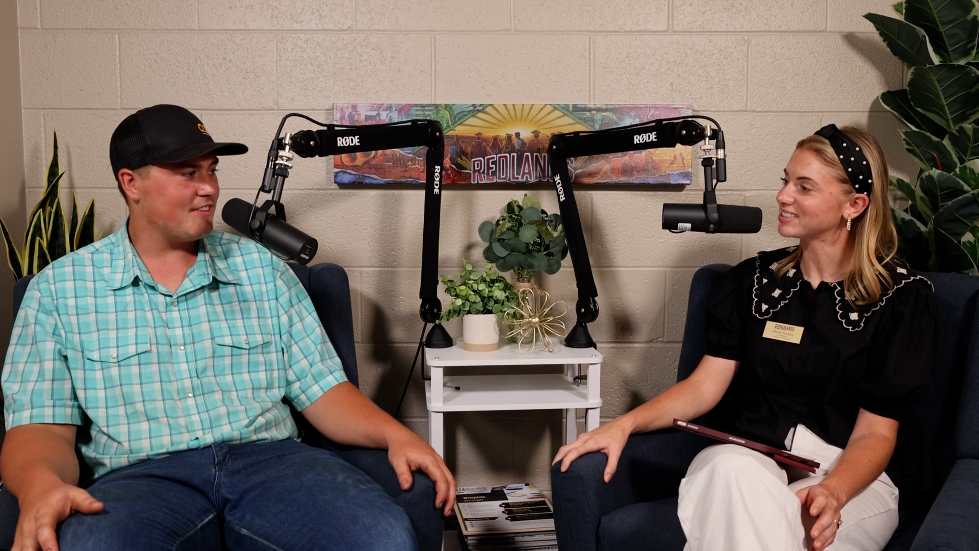 Man, left, and woman, right, sit next to microphones